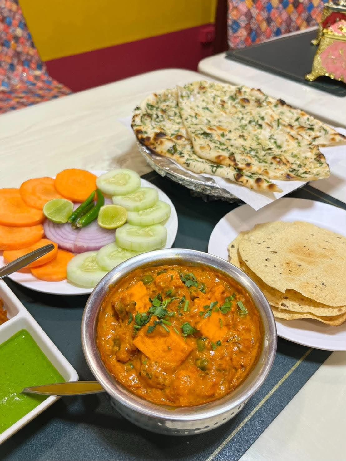 Paneer curry served with garlic naan, paratha and salad